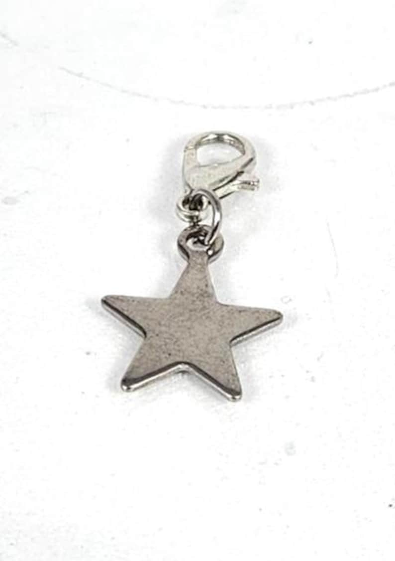 May include: A silver-colored star charm with a lobster clasp. The five-pointed star is a simple, classic design, perfect for jewelry making or adding to a keychain. The charm is made of metal.