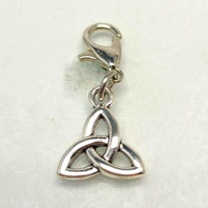 May include: A silver-colored charm with a Celtic knot design. The charm is attached to a clasp, allowing it to be easily added to a bracelet or necklace. The Celtic knot is a symbol of interconnectedness and eternity.