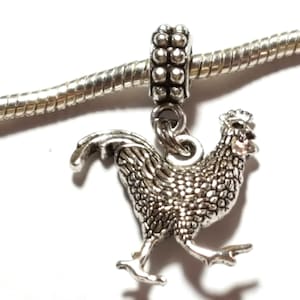 May include: Silver charm bracelet with a silver rooster charm. The rooster is facing right and has a detailed design.