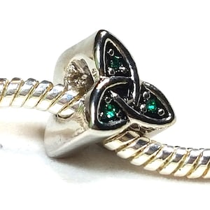 May include: Silver charm with a green Celtic knot design. The charm is attached to a silver bracelet.