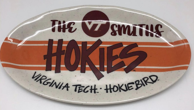May include: Oval ceramic platter with a speckled cream background. The platter features the words "THE SMITHS" and "HOKIES" in maroon, with orange stripes and the text "VIRGINIA TECH. HOKIEBIRD" in black.