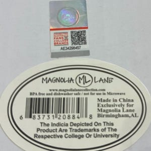 May include: A white sticker with the text "MAGNOLIA ML LANE" and a barcode. The sticker also includes the text "BPA free and dishwasher safe" and "Made in China". A holographic sticker is above the white sticker.
