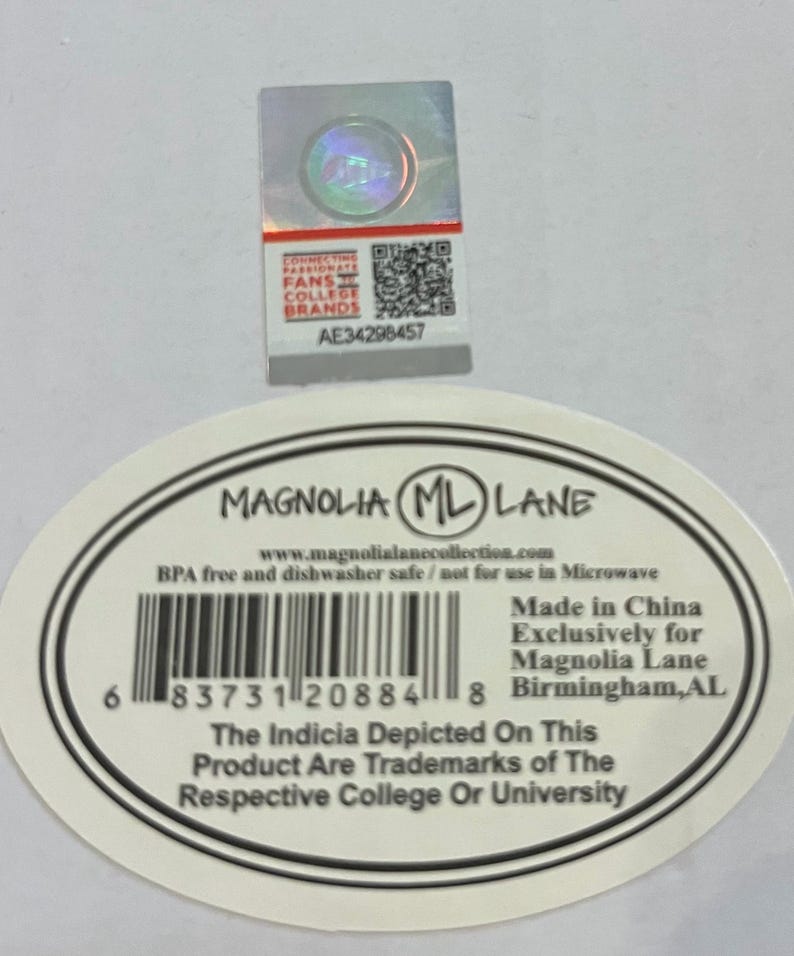 May include: A white sticker with the text "MAGNOLIA ML LANE" and a barcode. The sticker also includes the text "BPA free and dishwasher safe" and "Made in China". A holographic sticker is above the white sticker.