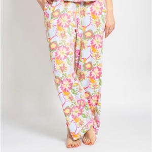 May include: Floral pajama pants in a light blue background with large pink, yellow, and orange flowers. The pants have a relaxed fit and a white trim. The image shows the pants from the waist down.