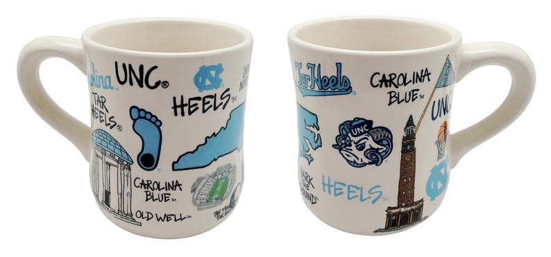 Op de afbeelding: Witte keramische mok met een gebogen handvat, met illustraties en tekst in Carolina blauw en zwart. Het ontwerp bevat de woorden "UNC", "Tar Heels" en "Carolina Blue", samen met een voetafdruk, een ram en een kaart van North Carolina.