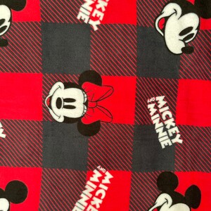 May include: Red and black plaid fabric with a repeating pattern of Mickey Mouse and Minnie Mouse. The text "Mickey and Minnie" is printed in white on the fabric.