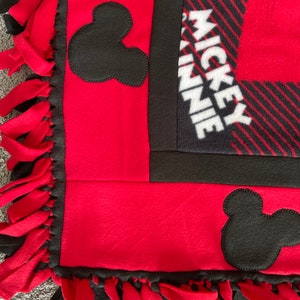 May include: Red and black fleece blanket with Mickey Mouse and Minnie Mouse ears and the text "Mickey Minnie" on the blanket.