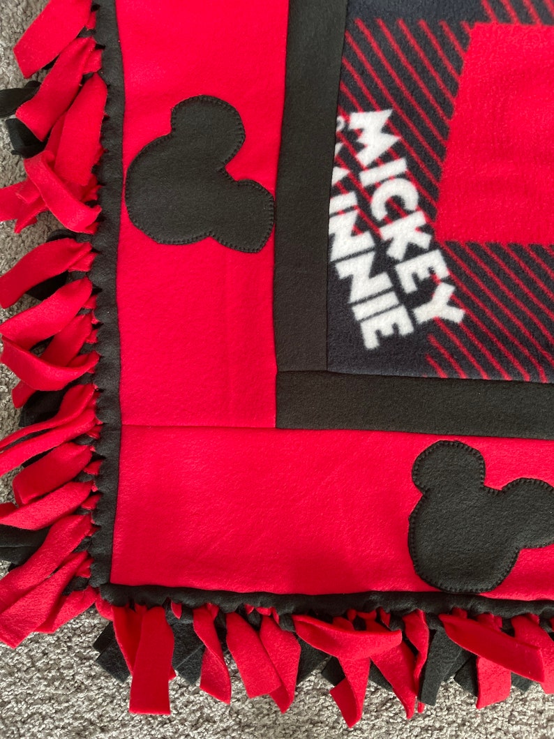 May include: Red and black fleece blanket with Mickey Mouse and Minnie Mouse ears and the text "Mickey Minnie" on the blanket.