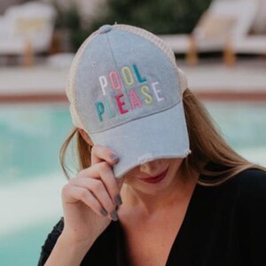 May include: A light blue trucker hat with a mesh back and the embroidered text "POOL PLEASE" in colorful letters. The hat has a distressed brim and a casual style, perfect for sunny days.
