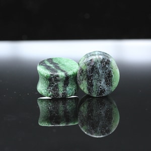 May include: Two green and black striped stone ear gauges. The gauges are round and have a smooth, polished finish.