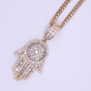 Close-up of real gold Hamsa charm with smooth finish and symbolic hand design. Mini Hamsa hand gold pendant shown on gold necklace chain for layering.