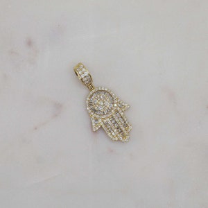 10k solid gold Hamsa hand charm pendant for protection, mini size fine jewelry. 10k gold Hamsa charm styled with beach-inspired gold jewelry on neutral background