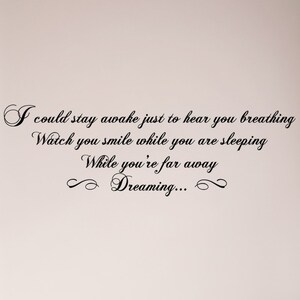 May include: Black and white cursive text on a light pink background. The text reads: "I could stay awake just to hear you breathing Watch you smile while you are sleeping While you're far away Dreaming..."