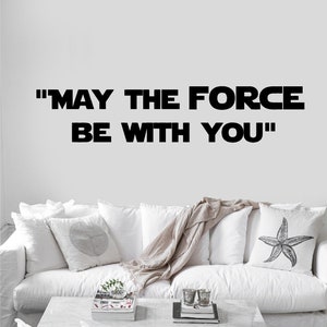 May include: White couch with throw pillows and a throw blanket. The wall behind the couch has a black vinyl decal that reads "MAY THE FORCE BE WITH YOU".