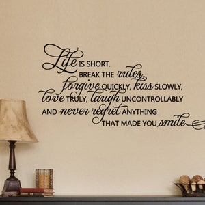 May include: Black and white wall decal with a cursive font quote that reads "Life is short. Break the rules, forgive quickly, kiss slowly, love truly, laugh uncontrollably and never regret anything that made you smile."
