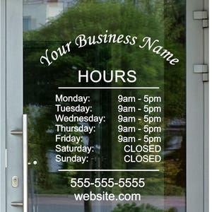 May include: A white sign on a glass door with the text "Your Business Name" and "HOURS" in a cursive font. The sign lists business hours for each day of the week, with the hours for Monday through Friday being 9am to 5pm. Saturday and Sunday are listed as "CLOSED". The sign also includes a phone number and website address.