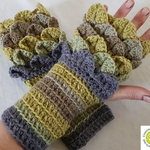 May include: A pair of crocheted fingerless gloves with a textured, leafy design in shades of green, brown, and gray. The gloves have a striped cuff in the same colors.