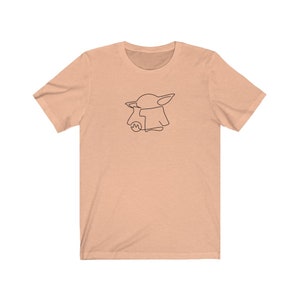 May include: A peach-colored t-shirt with a black line drawing of a cartoon character with large ears and a robe.