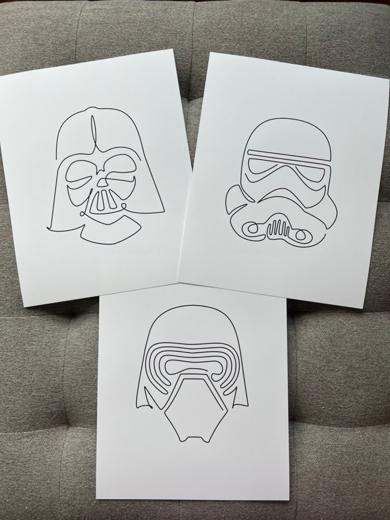 May include: Three black and white line drawings of Star Wars characters: Darth Vader, a Stormtrooper, and Kylo Ren. The drawings are on white paper.