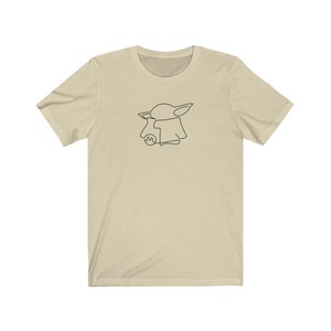 May include: A beige t-shirt with a black line drawing of a character from the Star Wars franchise, The Mandalorian, known as "The Child" or "Baby Yoda".