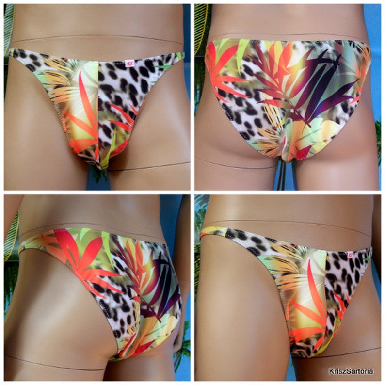 May include: A pair of colorful men's swim briefs with a tropical print featuring orange, yellow, green, and brown leaves on a white background. The briefs have a low rise and a cheeky cut.