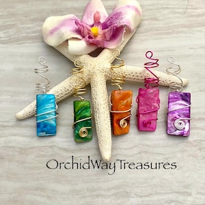 May include: Five rectangular pendants in shades of blue, green, orange, pink, and purple, each with a unique swirling pattern. The pendants are wire-wrapped and topped with a spiral design. The text "OrchidWayTreasures" is at the bottom.