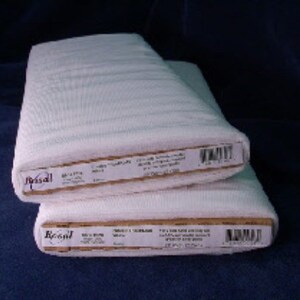 Puede incluir: Dos rollos de tela blanca apilados. La tela está enrollada y parece texturizada. Cada rollo tiene una etiqueta con texto y un código de barras. Sobre un fondo azul oscuro.