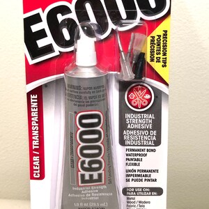 May include: E6000 industrial strength adhesive in a clear tube, 1.0 fl oz (29.5 mL). The packaging is red and white, with the product name prominently displayed. Includes precision tips for application.