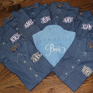 May include: Nine denim shirts with white embroidery. The shirts have different monograms on the front. One shirt has the word "Bride" embroidered on the back.