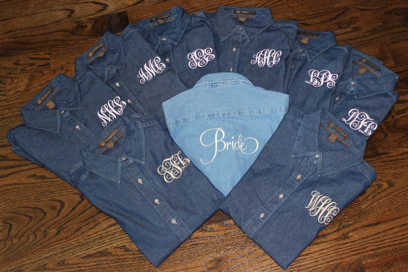 May include: Nine denim shirts with white embroidery. The shirts have different monograms on the front. One shirt has the word "Bride" embroidered on the back.