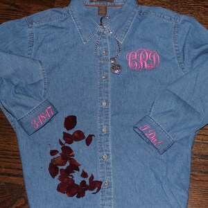 K&ouml;nnte beinhalten: Ein blaues Jeanshemd mit rosa Stickereien an den Manschetten und der Brust. Die Manschetten sagen "I Do!" und "3-18-17". Die Bruststickerei ist ein Monogramm mit den Buchstaben "C.R.O.".