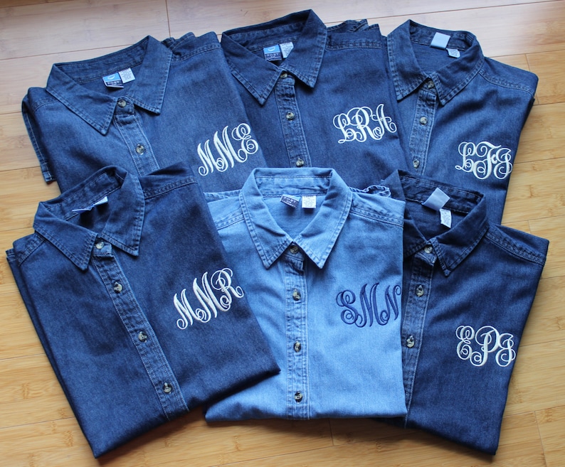 K&ouml;nnte beinhalten: Sieben Jeanshemden mit wei&szlig;en Stickereien. Jedes Hemd hat eine andere Monogramm-Stickerei auf der linken Brust.