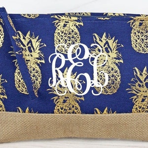 May include: A blue canvas zippered pouch with a gold pineapple print and a white monogram "RCL". The pouch has a brown burlap bottom.