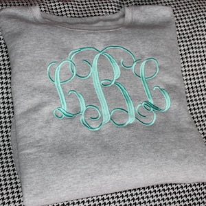 May include: A gray sweatshirt with a teal embroidered monogram of the letters "BBL".