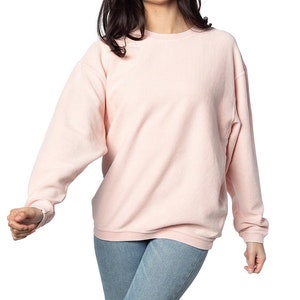 May include: A pale pink, long-sleeved, ribbed sweatshirt with a crew neck.