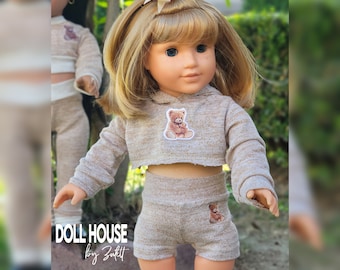 May include: A doll wearing a tan cropped hoodie and matching shorts set, each adorned with a small teddy bear patch. The doll has blonde hair and blue eyes. The text "DOLL HOUSE by Zuktt" is visible in the lower left corner.