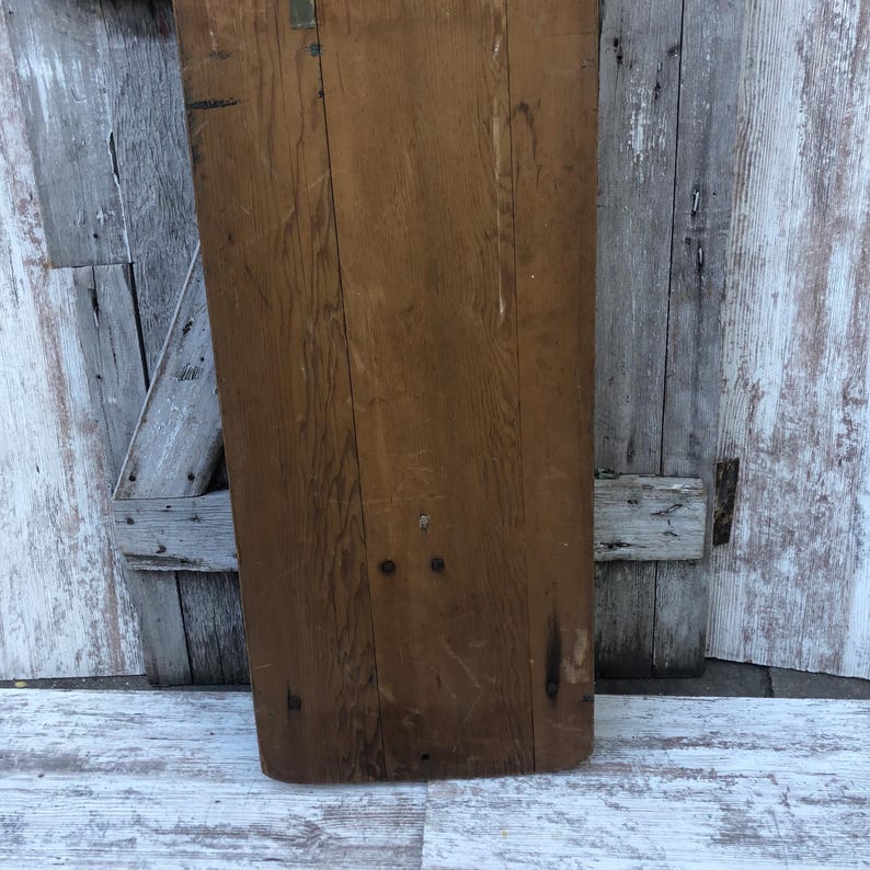 K&ouml;nnte beinhalten: Nahaufnahme einer Holzplatte mit nat&uuml;rlicher Holzmaserung. Die Platte ist rechteckig und hat eine leicht abgerundete Kante. Sie hat ein paar Nagell&ouml;cher und weist Gebrauchsspuren auf.