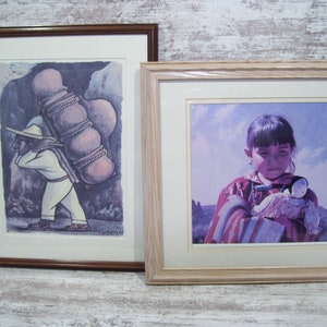 May include: Two framed prints, one depicting a person carrying a large stack of clay pots on their back, the other depicting a young girl holding a doll. Both prints are in a muted color palette.