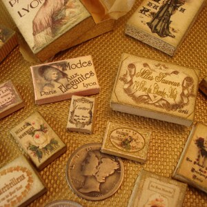 Peut inclure: Une collection de bo&icirc;tes de style vintage avec diff&eacute;rents motifs et textes. Les bo&icirc;tes sont en carton et ont un aspect vieilli. Le texte sur les bo&icirc;tes comprend "Modes Aux Elegantes", "Mlles Sauveur", "Cartier", et "An Merbeilleux".