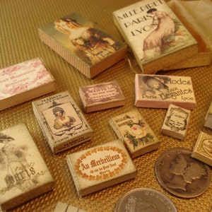Peut inclure: Une collection de bo&icirc;tes miniatures de style vintage avec diff&eacute;rents motifs et textes. Les bo&icirc;tes sont en carton et ont un fond cr&egrave;me avec des lettres brunes et noires. Certaines bo&icirc;tes pr&eacute;sentent des images de femmes en v&ecirc;tements vintage, tandis que d'autres ont des textes tels que "Modes aux Elegantes" et "Mille Direts Paris Lyon".