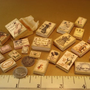 May include: A collection of miniature boxes with various designs and text, including "Mille Dilet Paris LVO", "Modes", "Paris", "Milletria 24 Rue de la Colombe Paris", and "Au Bon Marché".
