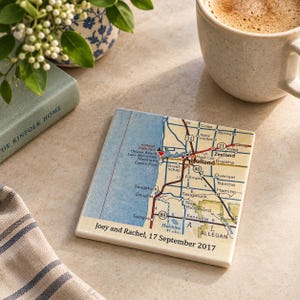 May include: A square ceramic coaster featuring a printed map of the Holland, Michigan area, including Lake Macatawa and surrounding towns. The map includes a small red heart icon and the text: Joey and Rachel, 17 September 2017.