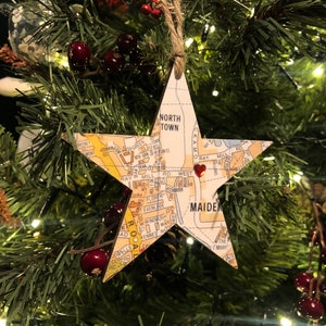 May include: A star-shaped Christmas ornament made from a paper map of Maiden, North Carolina. The ornament is decorated with a red heart sticker in the center.