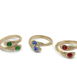 May include: Three gold-toned adjustable rings with a leaf design and a single gemstone on each. The rings feature green, blue, and red gemstones.