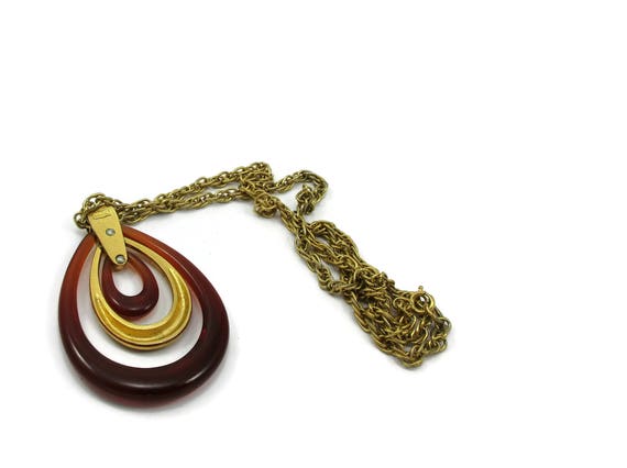 Gold metal necklace with brown and gold chamal cream lucite pendant. Signed Crown Trifari
