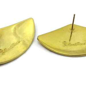 May include: A pair of gold-tone earrings with a fan-shaped design. The earrings are marked "Judith Jack" on the back.