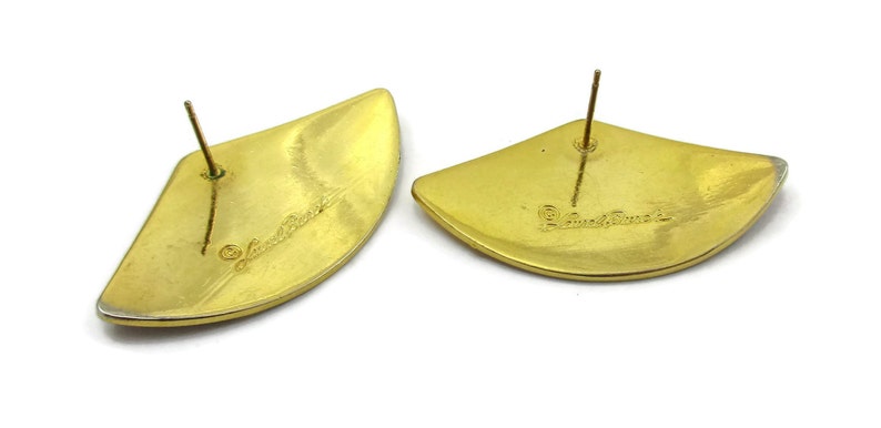 May include: A pair of gold-tone earrings with a fan-shaped design. The earrings are marked "Judith Jack" on the back.