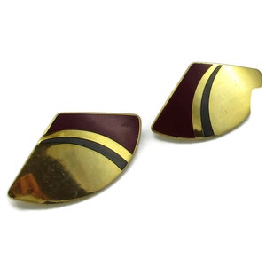 May include: A pair of gold tone earrings with a burgundy and black geometric design.