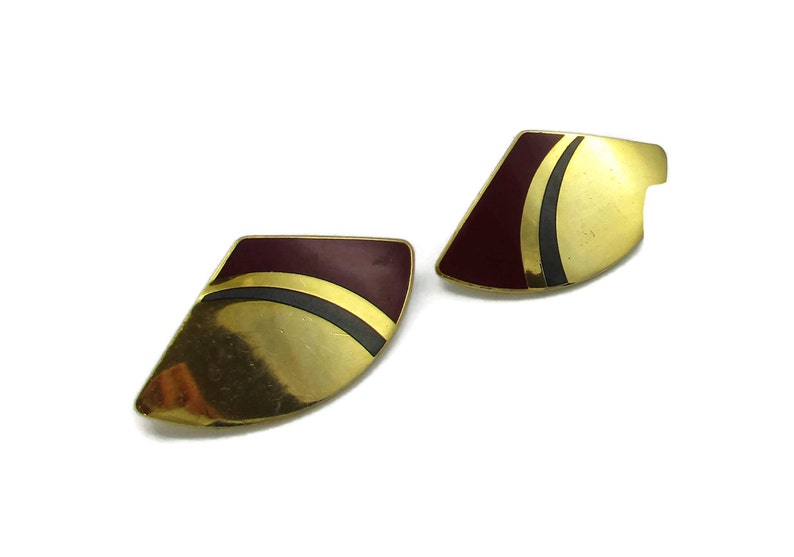 May include: A pair of gold tone earrings with a burgundy and black geometric design.