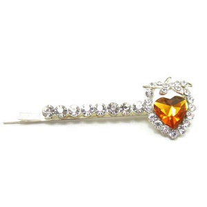 May include: A silver hair clip with a row of clear rhinestones and a heart-shaped orange rhinestone in the center.